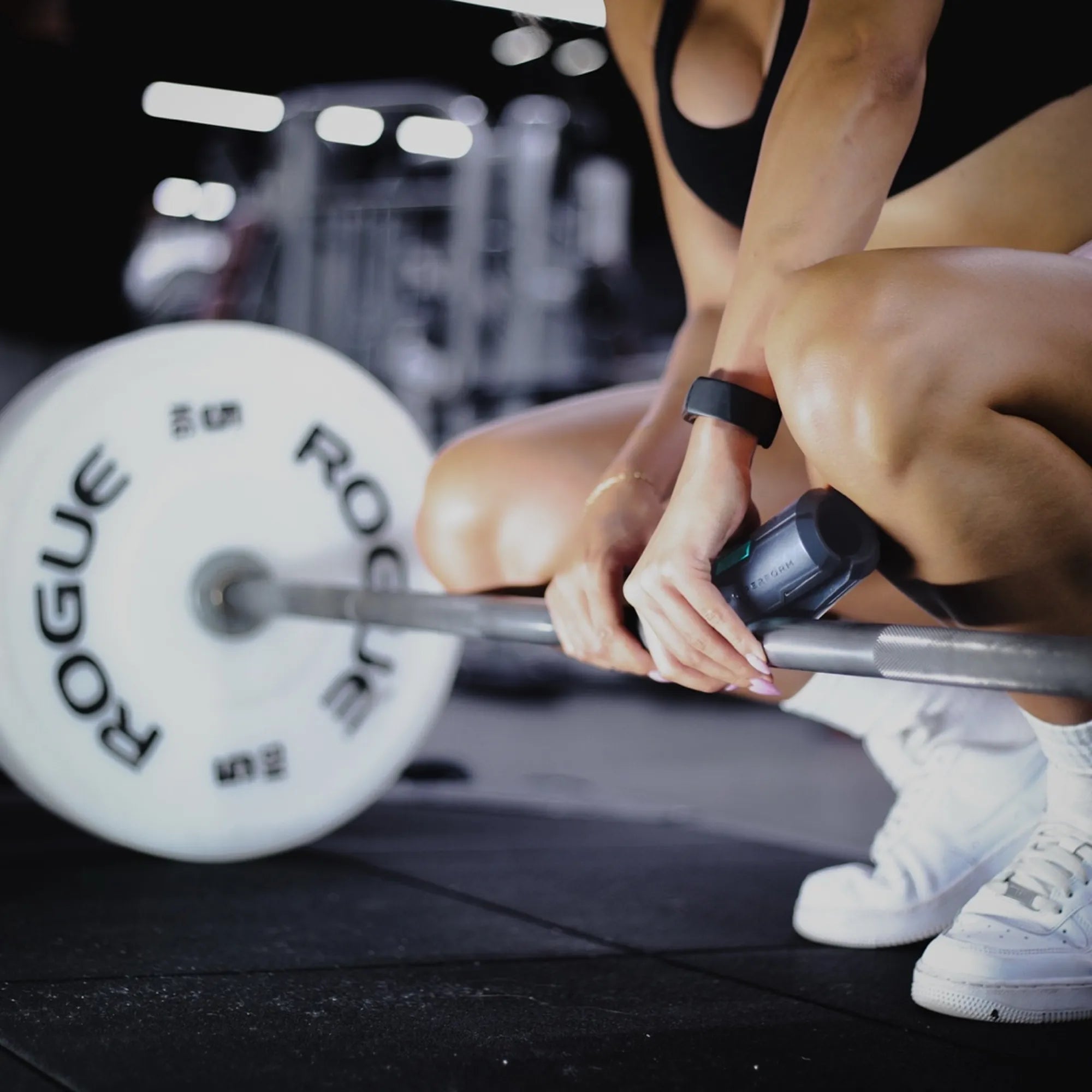 Female athlete setting up deadlift with Sniperform LevelUp Performance Grip on barbell in gym